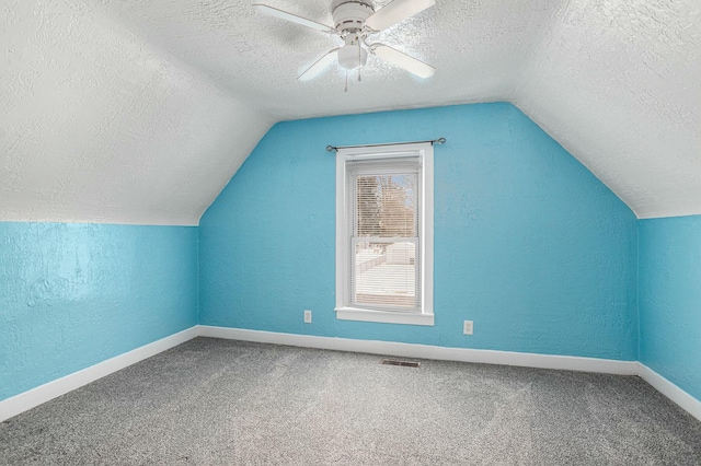 bonus room with vaulted ceiling, carpet floors, and a textured ceiling