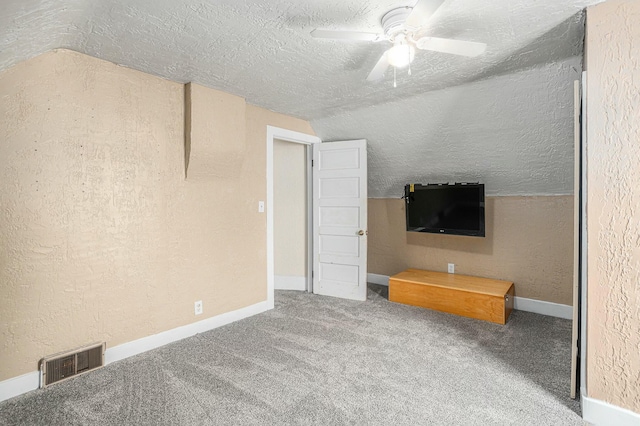 unfurnished bedroom with a textured ceiling, carpet floors, ceiling fan, and lofted ceiling