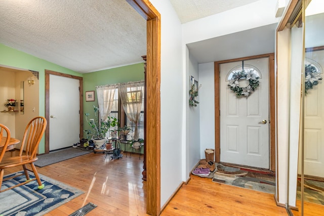 entryway featuring lofted ceiling, light hardwood / wood-style flooring, and a textured ceiling