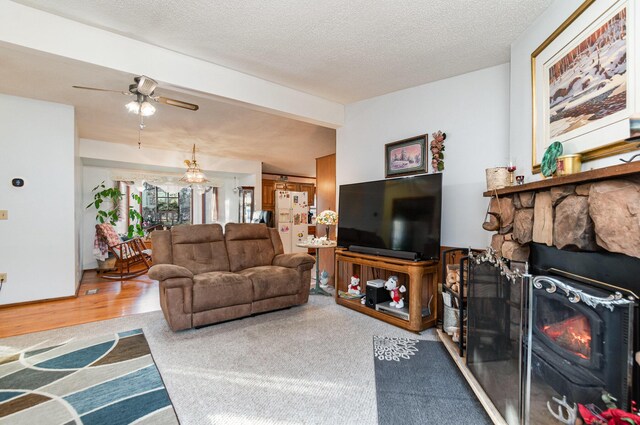 living room with ceiling fan, a fireplace, carpet floors, and a textured ceiling