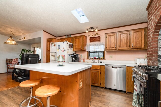 kitchen featuring a breakfast bar, appliances with stainless steel finishes, light wood-type flooring, and a skylight