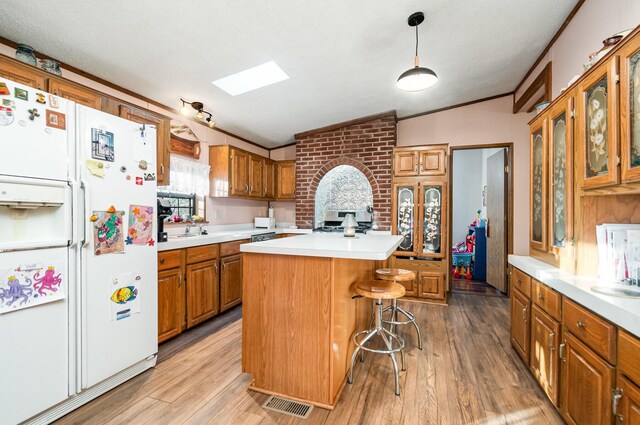 kitchen featuring vaulted ceiling with skylight, a kitchen island, white fridge with ice dispenser, and light hardwood / wood-style floors