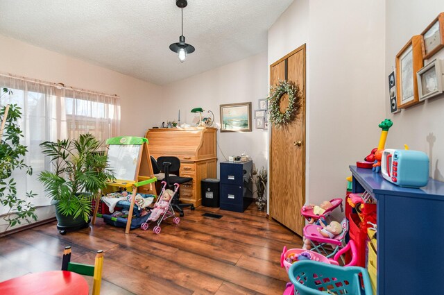 playroom with dark wood-type flooring and a textured ceiling