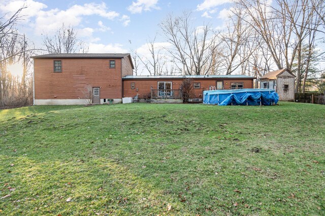 rear view of house with a lawn and a covered pool