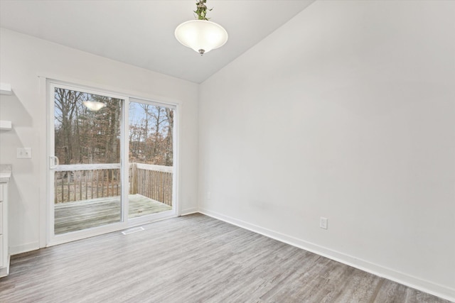 spare room featuring vaulted ceiling and light hardwood / wood-style flooring