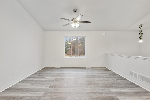 empty room with ceiling fan, light hardwood / wood-style flooring, and vaulted ceiling