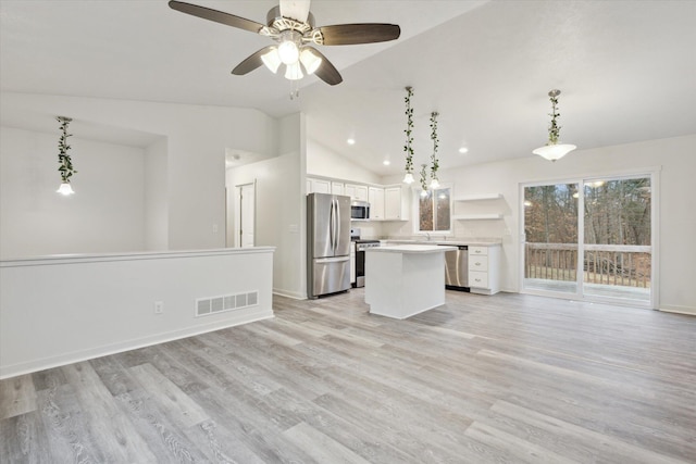 kitchen featuring a center island, vaulted ceiling, decorative light fixtures, white cabinetry, and stainless steel appliances