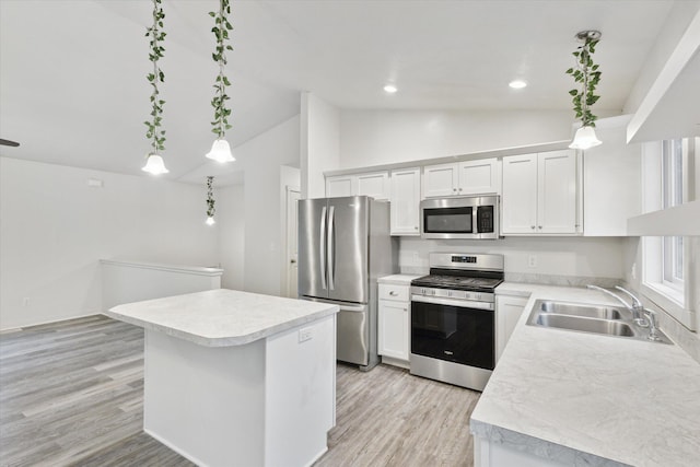 kitchen featuring appliances with stainless steel finishes, sink, decorative light fixtures, white cabinets, and lofted ceiling