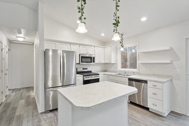 kitchen featuring sink, stainless steel appliances, lofted ceiling, decorative light fixtures, and white cabinets