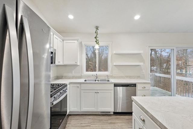 kitchen with appliances with stainless steel finishes, decorative light fixtures, white cabinetry, and sink