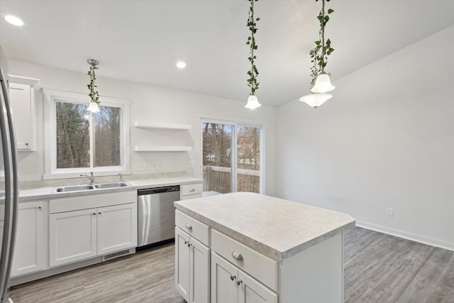 kitchen featuring pendant lighting, dishwasher, white cabinets, sink, and a kitchen island