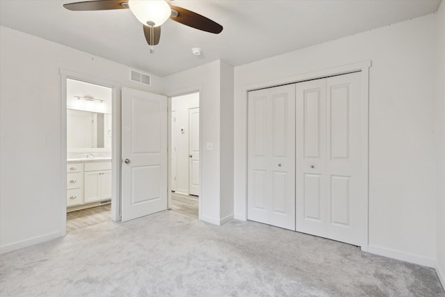 unfurnished bedroom with ceiling fan, ensuite bath, light carpet, and a closet