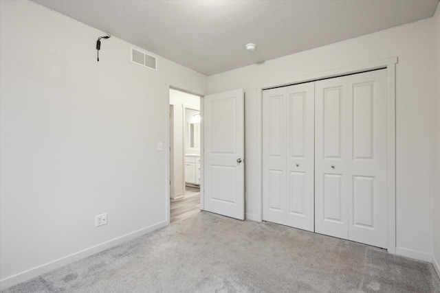 unfurnished bedroom featuring light carpet and a closet