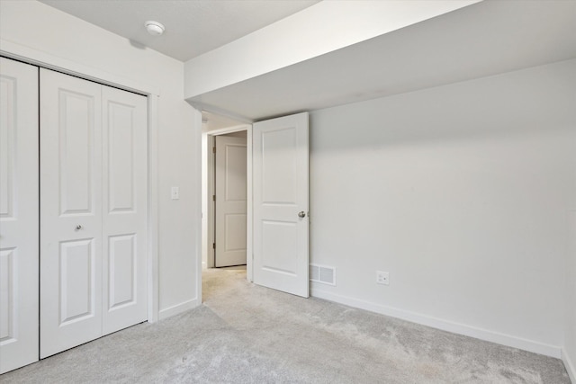 unfurnished bedroom featuring light carpet and a closet