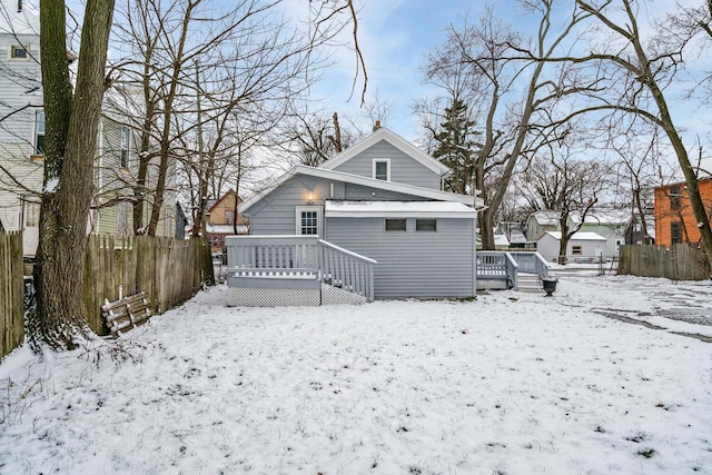 snow covered rear of property with a deck