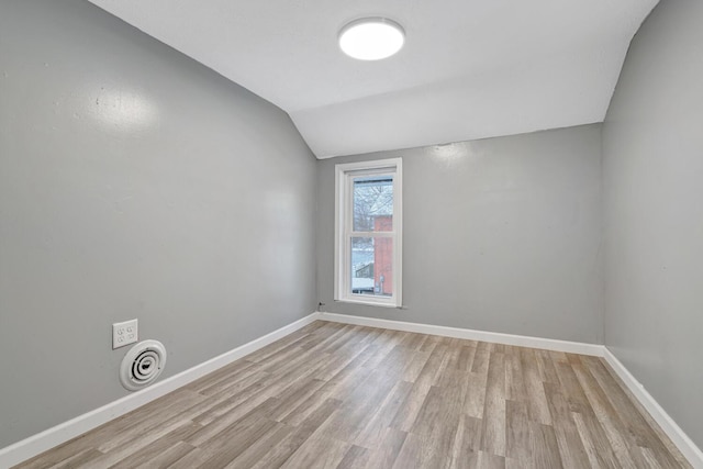 unfurnished room with light wood-type flooring and lofted ceiling