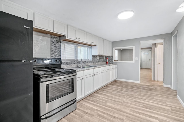 kitchen with black refrigerator, sink, electric range, tasteful backsplash, and white cabinetry