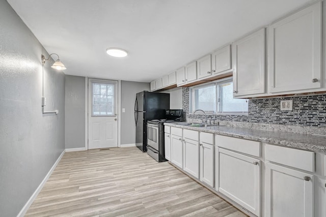 kitchen with decorative backsplash, light stone counters, sink, white cabinets, and stainless steel range with electric cooktop