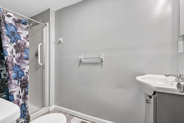 bathroom with vanity, a textured ceiling, toilet, and walk in shower