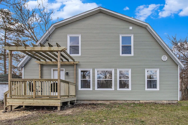 rear view of property featuring a pergola, a wooden deck, and a lawn