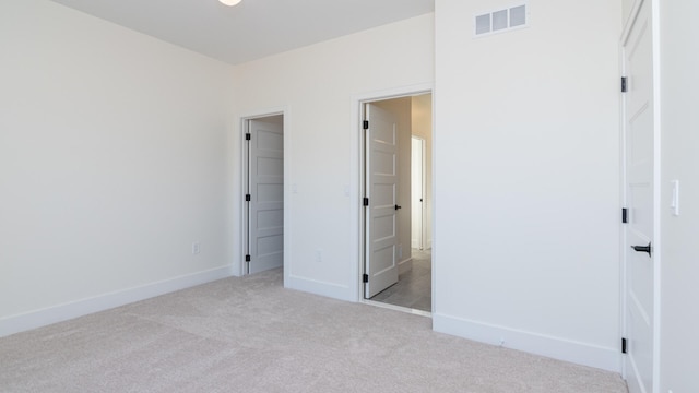 unfurnished bedroom with light colored carpet and a closet