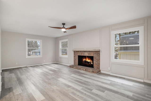 unfurnished living room with ceiling fan, a baseboard radiator, a fireplace, and light hardwood / wood-style floors