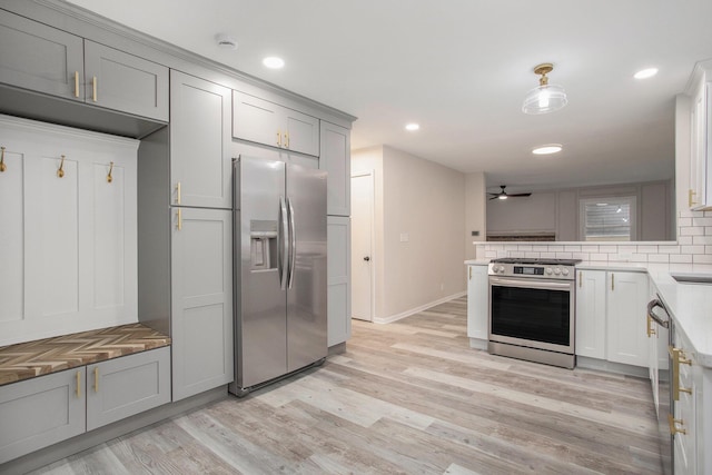 kitchen with gray cabinetry, ceiling fan, decorative backsplash, appliances with stainless steel finishes, and light wood-type flooring