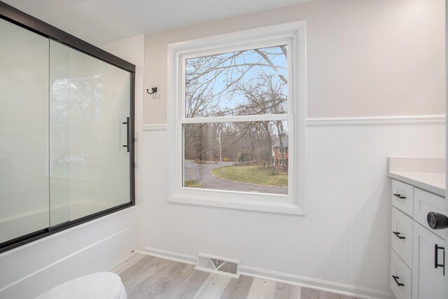 full bathroom with enclosed tub / shower combo, vanity, toilet, and hardwood / wood-style floors