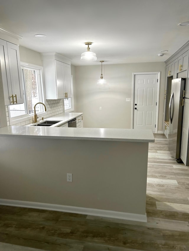 kitchen with appliances with stainless steel finishes, pendant lighting, white cabinetry, sink, and backsplash