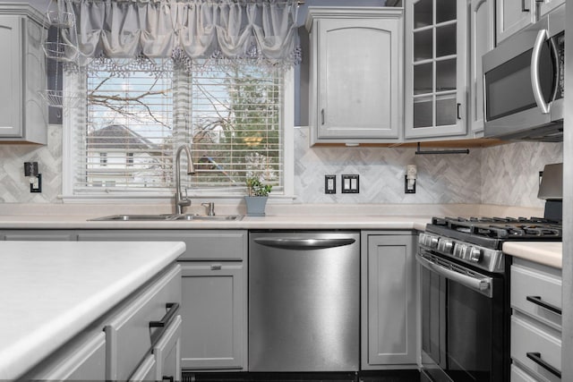 kitchen featuring backsplash, gray cabinets, sink, and appliances with stainless steel finishes