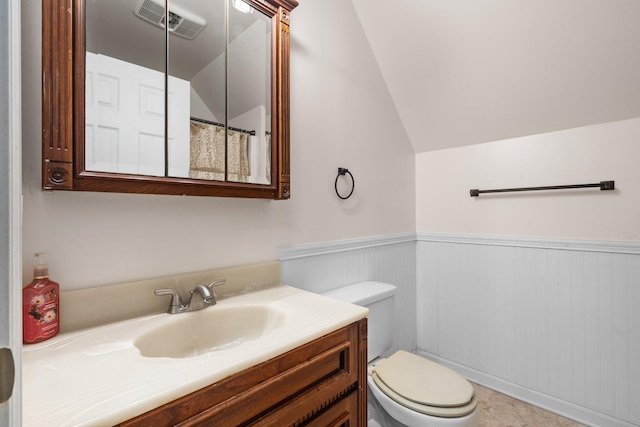 bathroom with tile patterned flooring, vanity, vaulted ceiling, and toilet