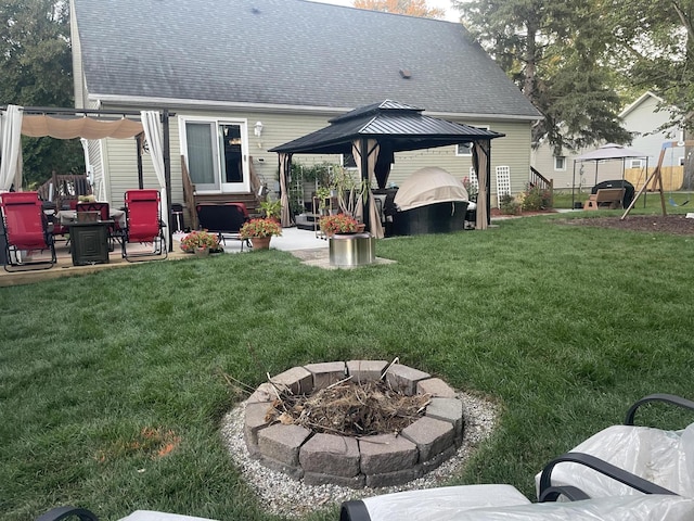 back of property featuring a gazebo, a patio area, an outdoor fire pit, and a lawn