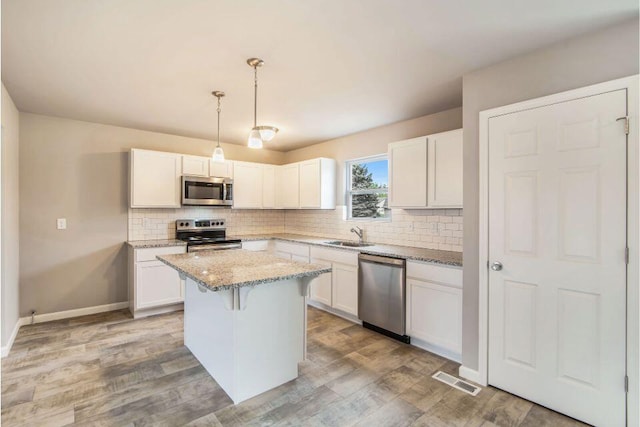 kitchen featuring white cabinets, a kitchen island, hanging light fixtures, and appliances with stainless steel finishes