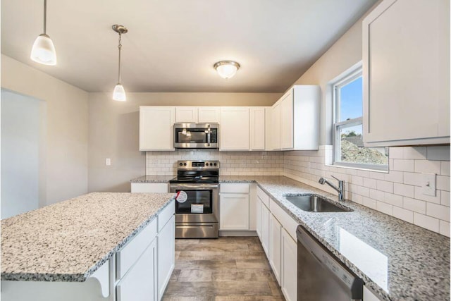 kitchen with white cabinets, decorative light fixtures, sink, and stainless steel appliances