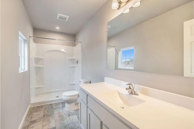 bathroom with a shower, toilet, vanity, and hardwood / wood-style flooring