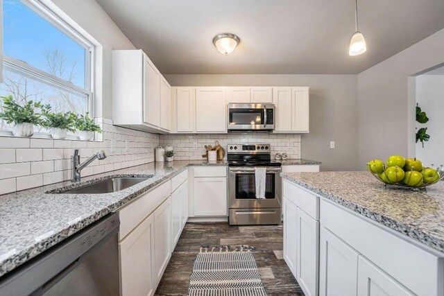 kitchen featuring pendant lighting, sink, white cabinets, and stainless steel appliances