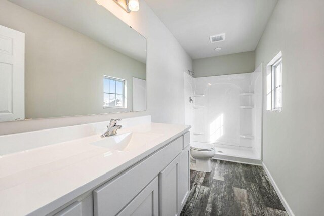 bathroom with wood-type flooring, vanity, toilet, and walk in shower