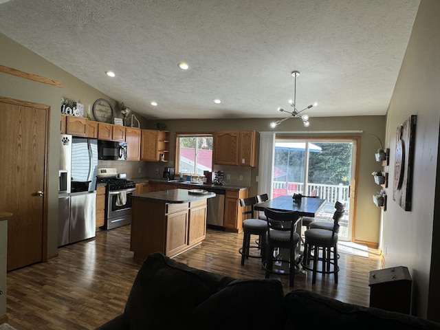 kitchen with tasteful backsplash, vaulted ceiling, pendant lighting, a kitchen island, and stainless steel appliances