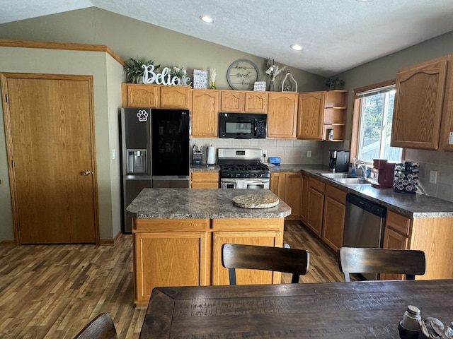 kitchen featuring sink, vaulted ceiling, black appliances, and a kitchen island