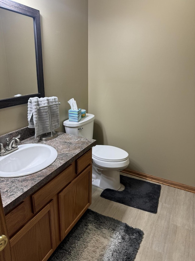 bathroom featuring toilet, vanity, and hardwood / wood-style floors