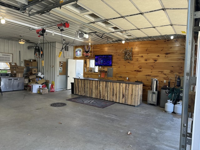 garage featuring a garage door opener, electric panel, wooden walls, and ceiling fan