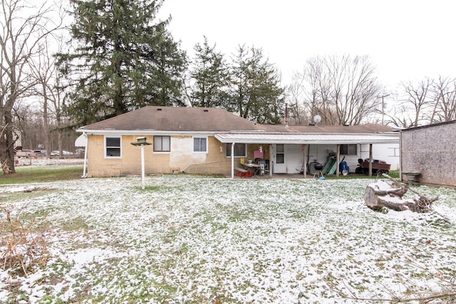 snow covered back of property with a patio area