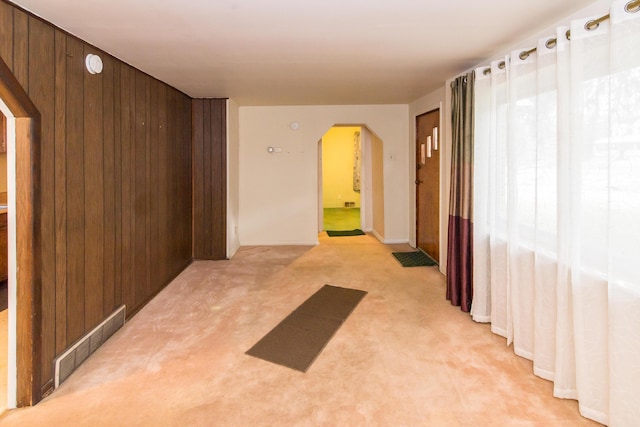 corridor featuring plenty of natural light, light carpet, and wooden walls