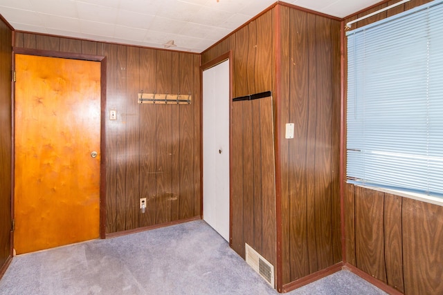 unfurnished bedroom with wood walls and light colored carpet