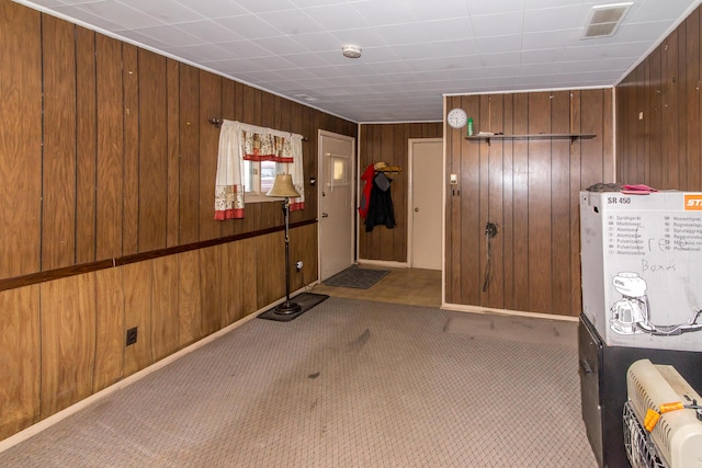 interior space featuring light colored carpet and wood walls