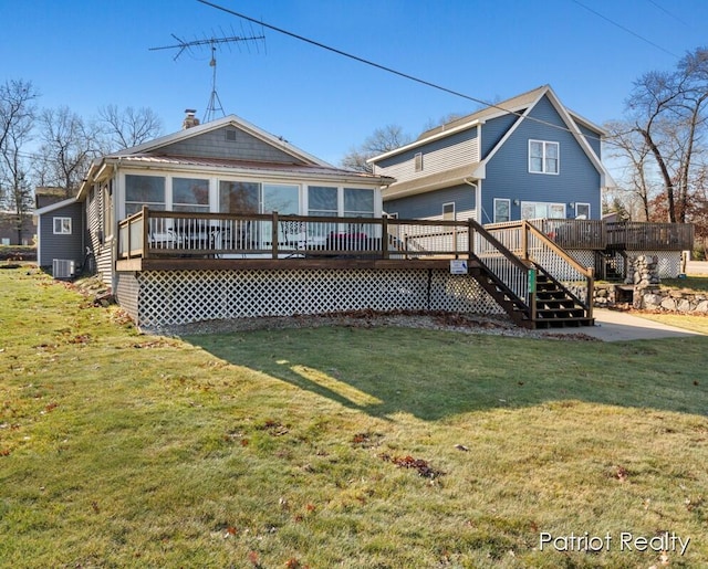 back of property featuring central air condition unit, a wooden deck, a sunroom, and a yard