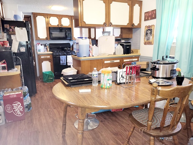 kitchen featuring black appliances, a textured ceiling, and wood-type flooring