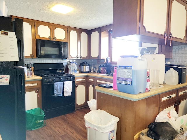 kitchen with black appliances, dark hardwood / wood-style flooring, backsplash, and a textured ceiling