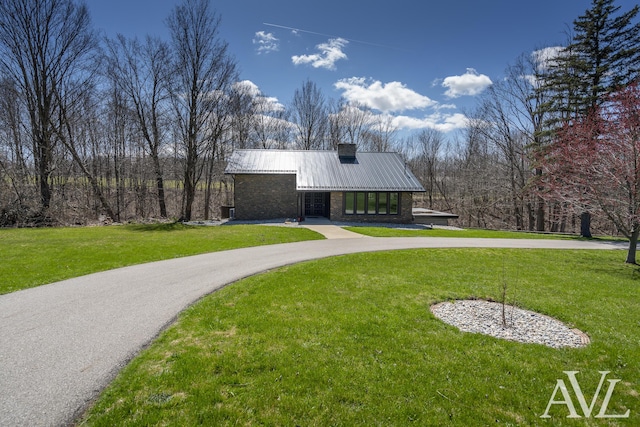view of front of home featuring curved driveway, a front yard, and metal roof