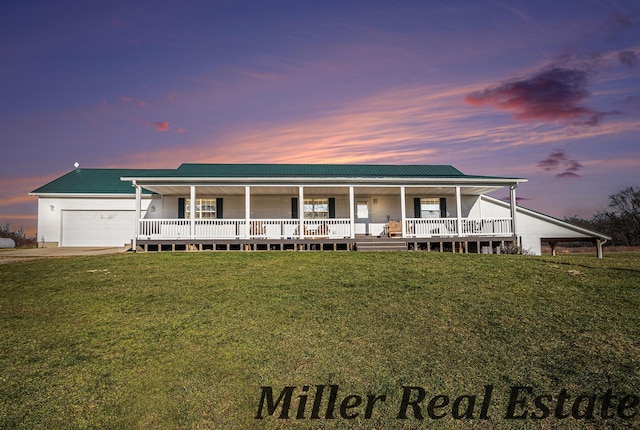 farmhouse featuring a lawn, a garage, and covered porch